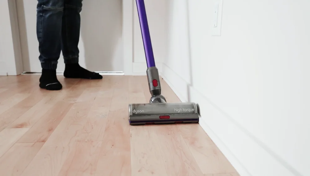Vacuuming a hardwood floor during home cleaning.