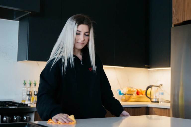 Home cleaner wiping a kitchen counter.