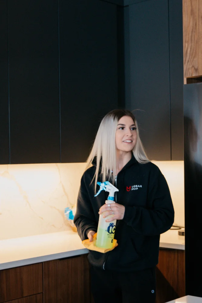 House cleaner holding supplies in a modern kitchen.