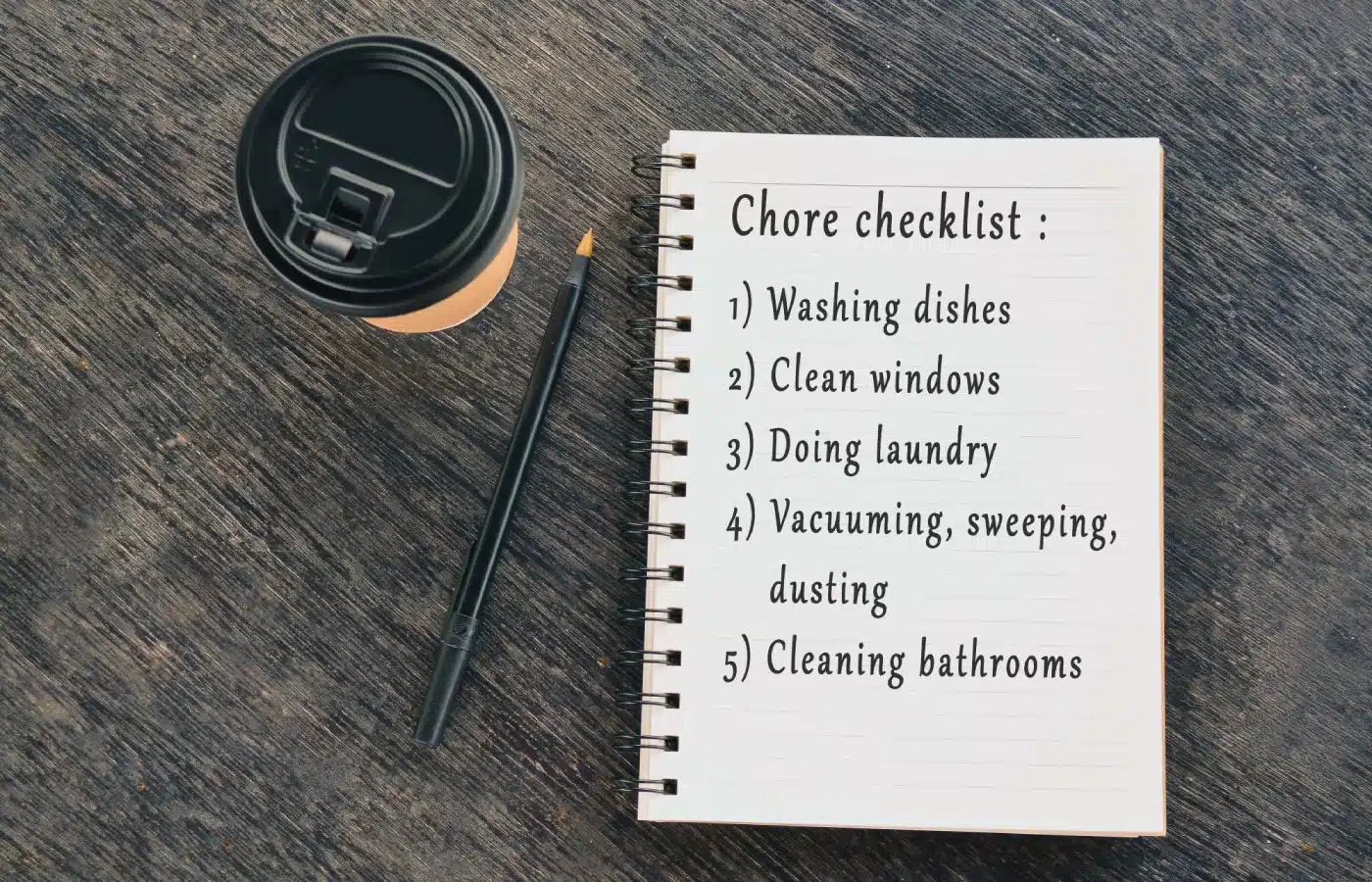 Cleaning checklist notebook with coffee and pen for Airbnb turnover prep.