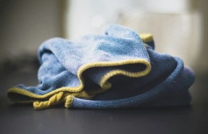 Blue microfiber cloth with yellow trim for household cleaning on a countertop