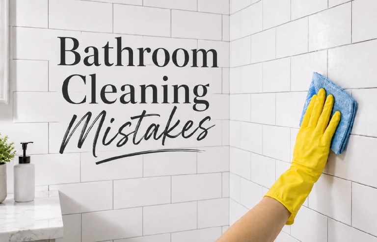 Person wearing a yellow glove cleaning white bathroom tile wall.
